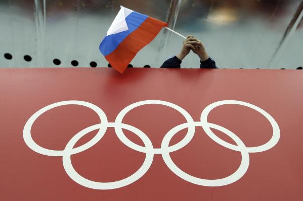 FILE - A Russian flag is held above the Olympic Rings at Adler Arena Skating Center during the Winter Olympics in Sochi, Russia on Feb. 18, 2014. Russia and its ally Belarus have been invited to compete at the Asian Games in the next step to qualify athletes for next year's Paris Olympics. One year after the invasion of Ukraine began, Russia's reintegration into the world of sports threatens to create the biggest rift in the Olympic movement since the Cold War. (AP Photo/David J. Phillip, File)