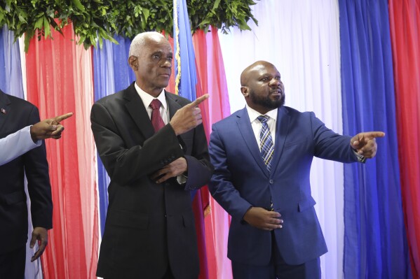 Edgard Leblanc fils, left, and Smith Augustin prepare to pose for a group photo with the transition council after appointing fils as president in Port-au-Prince, Haiti, Tuesday, April 30, 2024. The transition council will act as president the country's presidency until it can hold presidential elections sometime before its dissolution, which must take place by February 2026. (AP Photo/Odelyn Joseph)