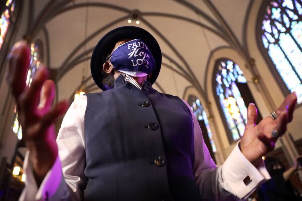 A parishioner wears a face mask saying "Faith Hope Love" while she prays during a Sunday church service at St. Sabina Catholic Church in the Auburn Gresham neighborhood in Chicago, Sunday, March 7, 2021.(AP Photo/Shafkat Anowar)