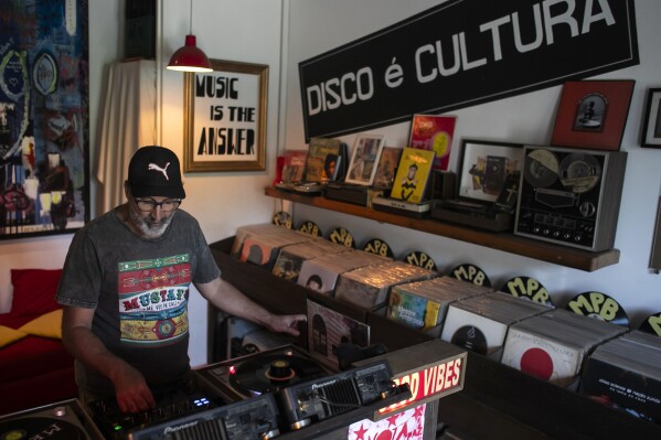 Deejay Mustafa Baba-Aissa, originally from Algeria, adjusts his sound system after placing a vinyl record on a turntable in his Vinil do Mustafa record shop, in Rio de Janeiro, Brazil, Friday, April 19, 2024. Vinyl records in Brazil outsold CDs and DVDs for the first time last year. (AP Photo/Bruna Prado)