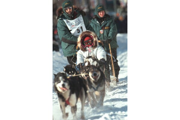 FILE - In this March 6, 1999, file photo, soap opera star Susan Lucci takes a ride in the sled of musher Rick Mackey at the start of the 27th Iditarod Trail Sled Dog Race in Anchorage, Alaska. Mackey, the winner of the 1983 Iditarod Trail Sled Dog Race, has died of lung cancer, his daughter Brenda told The Associated Press, Wednesday, May 11, 2024. Mackey, who died Monday, May 13, was 71. (AP Photo/Al Grillo, File)