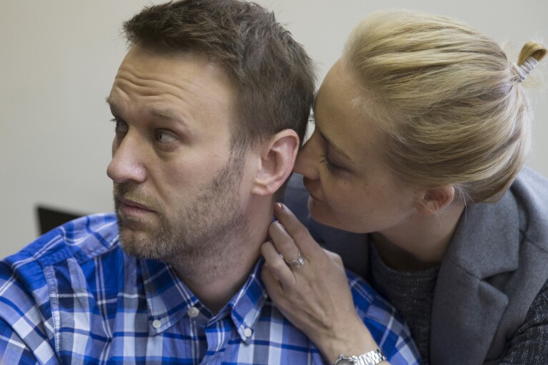 FILE - Russian opposition activist Alexei Navalny and his wife Yulia talk in a courtroom before the hearing in Moscow, Russia on April 23, 2015. Russia’s prison agency says that imprisoned opposition leader Alexei Navalny has died. He was 47. The Federal Prison Service said in a statement that Navalny felt unwell after a walk on Friday Feb. 16, 2024 and lost consciousness. (AP Photo/Pavel Golovkin, File)
