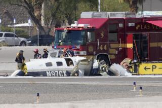 FILE - Officials investigate the wreckage of a plane at the site of a fatal crash at the North Las Vegas Airport, Sunday, July 17, 2022, in North Las Vegas, Nev. Two single-engine aircraft banked from opposite directions to land at the same time on the same runway in North Las Vegas last month when they collided in the air and tumbled to the ground, killing all four people aboard, a preliminary report by federal crash investigators showed Friday, Aug. 5, 2022. (AP Photo/John Locher, File)