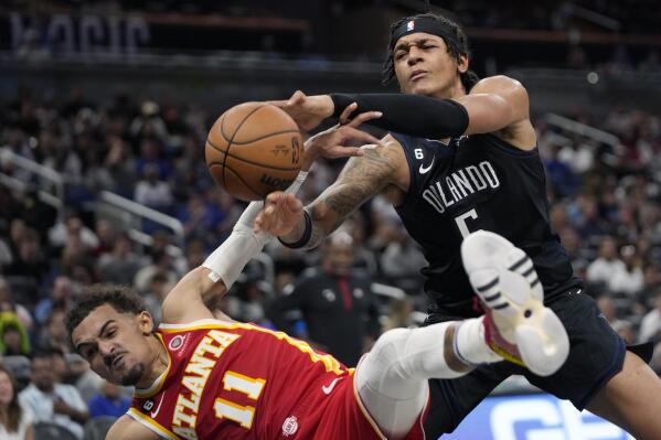 Atlanta Hawks' Trae Young, left, fouls Orlando Magic's Paolo Banchero (5) as he goes in for a shot during the second half of an NBA basketball game, Wednesday, Dec. 14, 2022, in Orlando, Fla. (AP Photo/John Raoux)