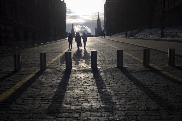 People walk on Red Square after sunrise with the St. Basil's Cathedral and the Spasskaya Tower and the Lenin Mausoleum in the background in Moscow, Russia, Saturday, Feb. 22, 2025. (AP Photo/Alexander Zemlianichenko)