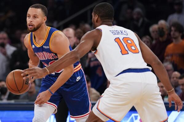 Golden State Warriors guard Stephen Curry (30) looks to move the ball around New York Knicks guard Alec Burks (18) during the first half of an NBA basketball game, Tuesday, Dec. 14, 2021, at Madison Square Garden in New York. (AP Photo/Mary Altaffer)