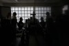 Anti-Mafia Force (DIA) leader Carla Durante, left, is silhouetted as she chats with her team in the electronic recording room at DIA headquarters in Lecce, Italy, Tuesday, May 21 2024. (AP Photo/Alessandra Tarantino)