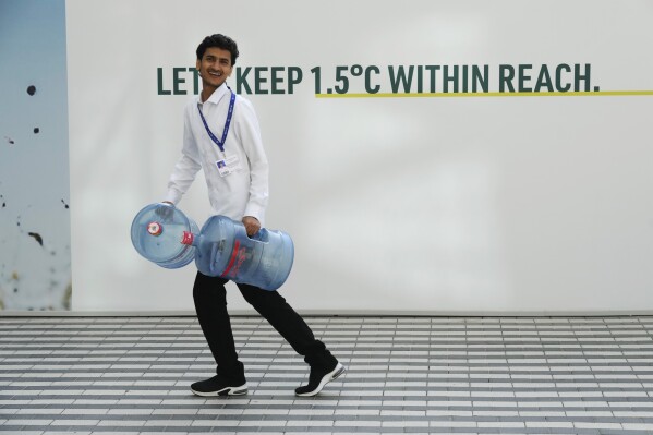 FILE - A man carries water containers ahead of the COP28 United Nations climate summit in Dubai, United Arab Emirates, Wednesday, Nov. 29, 2023.  (AP Photo/Peter DeJong, File)