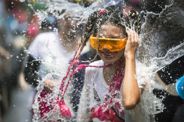 A bucket of water is splashed on a woman during the Songkran water festival to celebrate the Thai New Year, in Prachinburi Province, Thailand, April 13, 2024. (AP Photo/Wason Wanichakorn)