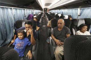 FILE - In this July 18, 2019 file photo, migrants sit in a bus that was organized by the Mexican government, which will take them from an immigration center in the border city of Nuevo Laredo to Monterrey, Mexico, after they were returned to Mexico by U.S. authorities. (AP Photo/Marco Ugarte, File)