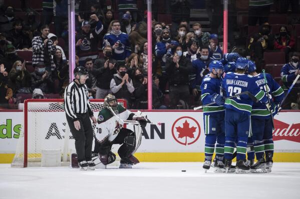 Arizona Coyotes goalie Karel Vejmelka (70) waits as Vancouver Canucks' J.T. Miller, Brock Boeser, Elias Pettersson, Oliver Ekman-Larsson and Bo Horvat celebrate Boeser's goal during the third period of an NHL hockey game Tuesday, Feb. 8, 2022, in Vancouver, British Columbia. (Darryl Dyck/The Canadian Press via AP)