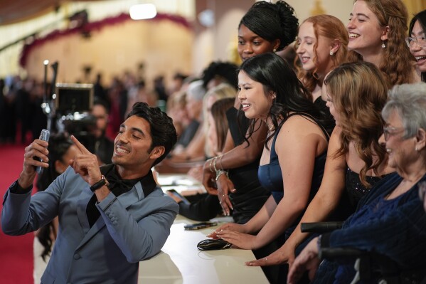 Taylor Zakhar Perez, left, takes a selfie with fans at the Oscars on Sunday, March 10, 2024, at the Dolby Theatre in Los Angeles. (AP Photo/John Locher)