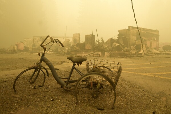 FILE - A trike stands near the burnt remains of a building destroyed by a wildfire near the Lake Detroit Market in Detroit, Ore., Sept. 11, 2020. A jury verdict that found power company PacifiCorp liable for devastating wildfires in Oregon in 2020 is highlighting the legal and financial risks utilities face if they fail to take proper precautions for climate change. (Mark Ylen/Albany Democrat-Herald via AP, File)
