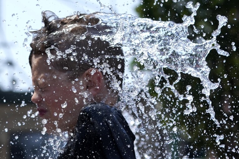 A boy cools off near a fountain on a hot day in Chicago, Sunday, June 16, 2024. (AP Photo/Nam Y. Huh)