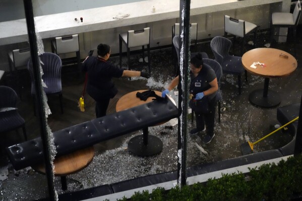 Trabalhadores limpam vidros quebrados em um restaurante no centro da cidade danificado por fortes tempestades na quinta-feira, 16 de maio de 2024, em Houston.  (Foto AP / David J. Phillip)