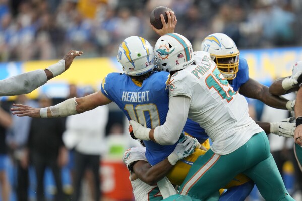 Los Angeles Chargers quarterback Justin Herbert (10) is sacked by Miami Dolphins linebacker Jaelan Phillips (15) during the fourth quarter of an NFL football game Sunday, Sept. 10, 2023, in Inglewood, Calif. (AP Photo/Ashley Landis)