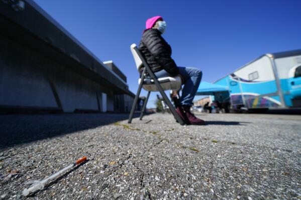A syringe is seen on the ground as Lisa McFadden waits to be treated near a Baltimore City Health Department RV, Monday, March 20, 2023, in Baltimore. The Baltimore City Health Department's harm reduction program uses the RV to address the opioid crisis, which includes expanding access to medication assisted treatment by deploying a team of medical staff to neighborhoods with high rates of substance abuse and offering buprenorphine prescriptions. (AP Photo/Julio Cortez)