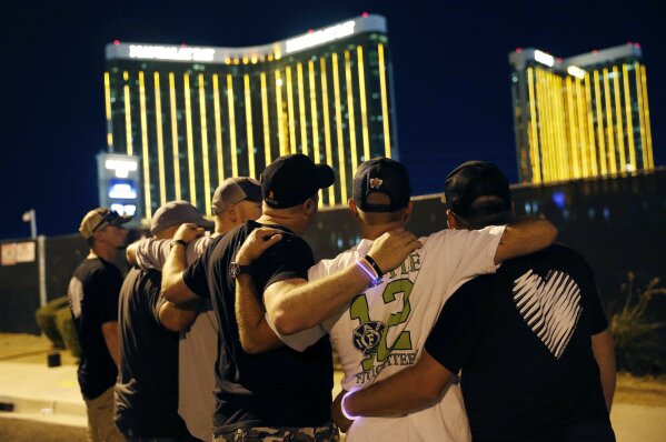
              Survivors return to the scene of a mass shooting on the first anniversary, Monday, Oct. 1, 2018, in Las Vegas. Hundreds of survivors of the Las Vegas mass shooting have formed a human chain around the shuttered site of a country music festival where a gunman opened fire last year. (AP Photo/John Locher)
            