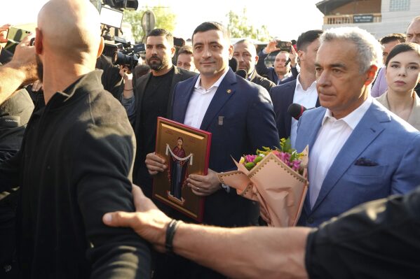 Presidential candidate George Simion, left, holds a religious icon as he walks with Calin Georgescu, winner of the first round of last year's annulled election, after casting his vote in the first round of the presidential election redo in Mogosoaia, Romania, Sunday, May 4, 2025. (AP Photo/Vadim Ghirda)