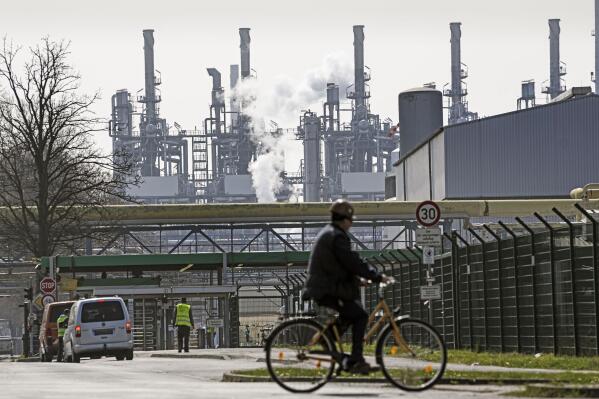 FILE -A worker rides his bicycle to the BP oil refinery Ruhr Oil in Gelsenkirchen, Germany, Monday, March 28, 2022. The German government said Wednesday it was triggering the early warning level for gas supplies amid concerns that Russia could cut off supplies unless it is paid in rubles. (AP Photo/Martin Meissner, file)