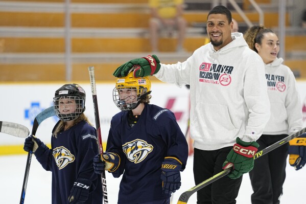 Minnesota Wild hockey player Ryan Reaves, right, of the NHL Player Inclusion Coalition pats Hayden Spalin on the head during a youth hockey clinic with NHL top draft prospects and members of the coalition, Tuesday, June 27, 2023, in Nashville, Tenn. (AP Photo/George Walker IV)