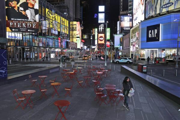 FILE - This March 16, 2020 file photo shows a woman walking through a lightly trafficked Times Square in New York. COVID-19 has shaken theater fans and shuttered all New York City's venues, including Broadway, which grossed $1.8 billion last season and attracted a record 15 million people. How Broadway — one the city's jewels — will reopen is still not clear. (AP Photo/Seth Wenig, FIle)