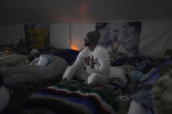 Diwaldo Salado, a retreat participant, sits on an air mattress during a breathwork session before the beginning of a Hummingbird Church ayahuasca ceremony, on Friday, Oct. 14, 2022, in Hildale, Utah. A rising demand for ayahuasca has spurred the formation of hundreds of groups like Hummingbird across the U.S. (AP Photo/Jessie Wardarski)