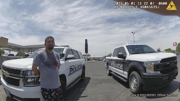 In this frame grab from body camera video provided by the Roswell Police Department, Tony Peralta leans against a police vehicle after turning himself in to authorities, in Roswell, N.M., May 1, 2023. Peralta called 911 to confess to the 2008 killing of his former landlord. (Roswell Police Department via AP)