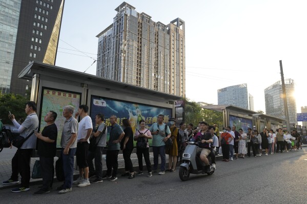 Residents line up for public transportation in Beijing, Tuesday, Aug. 15, 2023. Chinese leader Xi Jinping has called for patience in a speech released as the ruling Communist Party tries to reverse a deepening economic slump and said Western countries are 
