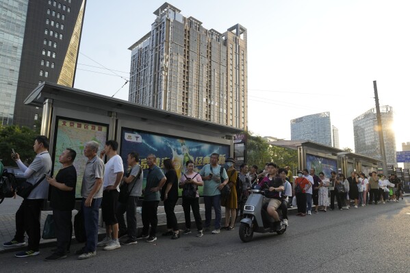 Residents line up for public transportation in Beijing, Tuesday, Aug. 15, 2023. Chinese leader Xi Jinping has called for patience in a speech released as the ruling Communist Party tries to reverse a deepening economic slump and said Western countries are "increasingly in trouble" because of their materialism and "spiritual poverty." (AP Photo/Ng Han Guan)