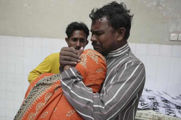 A family mourns next to the body of their family member, who was died in the stampede, at a morgue, in Karachi, Pakistan, Friday, March 31, 2023. Several people were killed in the deadly stampede at a Ramadan food distribution center outside a factory in Pakistan's southern port city of Karachi, police and rescue officials said. (AP Photo/Fareed Khan)