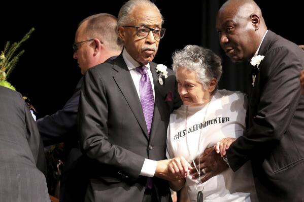 Rev. Al Sharpton, left, and attorney Benjamin Crump, right, escort Rebecca Payne to view her grandson's casket during the funeral service for 17-year-old Hunter Brittain, on Tuesday, July 6, 2021, at the Beebe High Schools Auditorium in Beebe, Ark. Brittain was shot by a Lonoke County Sheriff's Deputy during a traffic stop on June 23. (Tommy Metthe/The Arkansas Democrat-Gazette via AP)