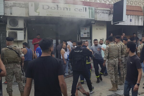 Lebanese soldiers and firefighters gather outside a mobile shop after what is believed to be the result of a walkie-talkie exploding inside it, in the southern port city of Sidon, Lebanon, Wednesday, Sept. 18, 2024. (AP Photo/Mohammed Zaatari, File)