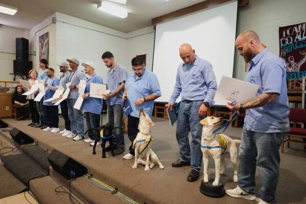 Jared Hansen, right, and other incarcerated men at the San Quentin Rehabilitation Center hold up their dog training certificates during a celebration in San Quentin, Calif., Friday, March 28, 2025. (AP Photo/Eric Risberg)