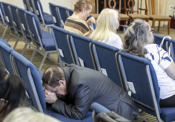 A congregant kneels in prayer at the Centro Cristiano El Pan de Vida, a mid-size Church of God of Prophecy congregation, in Kissimmee, Fla., Sunday, Feb. 2, 2025. (AP Photo/Alan Youngblood)