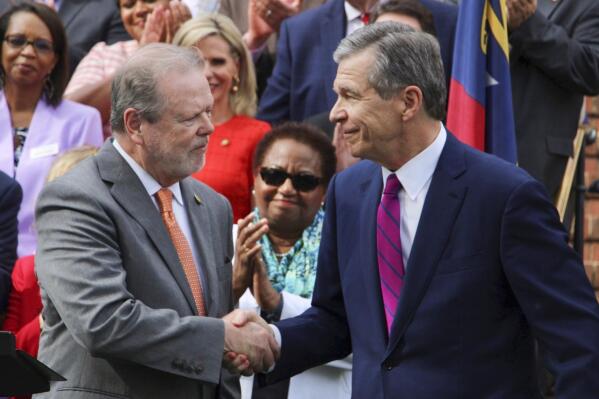 North Carolina Republican Senate leader Phil Berger, left, and Democratic Gov. Roy Cooper shake hands at a ceremony celebrating Medicaid expansion Monday, March 27, 2023, at the Executive Mansion in Raleigh, N.C. (AP Photo/Hannah Schoenbaum)