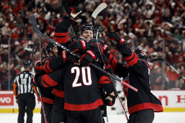 Carolina Hurricanes' Taylor Hall (71) leaps on top of the celebration for Sebastian Aho (20) game winning overtime goal during the second overtime period of Game 5 of an NHL hockey Stanley Cup first-round playoff series against the New Jersey Devils in Raleigh, N.C., Tuesday, April 29, 2025. (AP Photo/Karl DeBlaker)