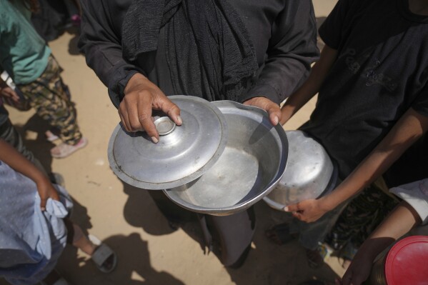A woman shows up her empty pot after a community kitchen ran out of donated food to distribute in Khan Younis, in the southern Gaza Strip, Friday, May 9, 2025. (AP Photo/Abdel Kareem Hana)