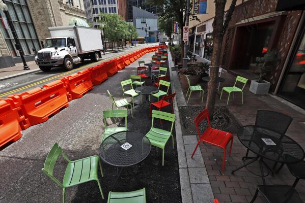 FILE - In this June 23, 2020, file photo orange barriers enclose chairs and tables that will be used for dining along Sixth Street between Liberty and Penn avenues in downtown Pittsburgh. A report by Moody’s Analytics, a private sector economic research firm, released Wednesday, June 24, is warning anew of continuing damage to the economy if Washington doesn’t deliver several hundred billion dollars in budget relief to states and local governments amid the coronavirus pandemic. (AP Photo/Gene J. Puskar, File)