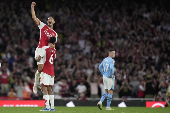 Arsenal's William Saliba, top, and Arsenal's Gabriel celebrate winning the English Premier League soccer match between Arsenal and Manchester City at the Emirates Stadium in London, Sunday, Oct. 8, 2023.(AP Photo/Kirsty Wigglesworth)
