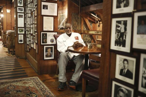 Angus Barn executive chef Walter Royal sits in his favorite spot in the Angus Barn, a Raleigh, N.C., institution, Wednesday, Feb. 19, 2020. Royal, the chef of a destination steakhouse in North Carolina who triumphed on “Iron Chef America” by cooking mostly southern dishes with ostrich meat, has died Monday, May 22, 2023, at the age of 67. The Angus Barn in Raleigh, where Royal served as executive chef since the 1990s, announced his passing on its website. (Juli Leonard/The News & Observer via AP)