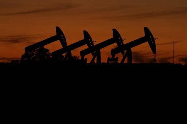Oil pump jacks operate at dusk near Barnes City, Texas, Wednesday, Nov. 1, 2023. The U.S. Securities and Exchange Commission weakened a proposed climate disclosure rule after strong pushback from companies and others, and will no longer require companies to report some greenhouse gas emissions. (AP Photo/Eric Gay)