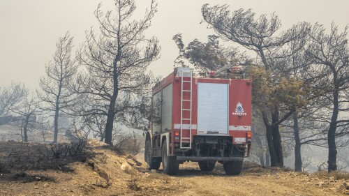 A fire-fighting vehicle makes its way through burnt trees during a forest fire, on the island of Rhodes, Greece, Sunday, July 23, 2023. Greek authorities say some 19,000 people have been evacuated from the Greek island of Rhodes as wildfires continue burning for a sixth day on three fronts. (Lefteris Diamanidis/InTime News via AP)