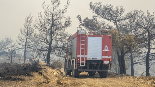 Un veicolo antincendio si fa strada attraverso alberi in fiamme durante un incendio nell'isola di Rodi, in Grecia, domenica 23 luglio 2023. Le autorità greche affermano che circa 19.000 persone sono state evacuate dall'isola greca di Rodi mentre gli incendi continuano per un sesto giorno su tre fronti.  (Lefteris Diamanidis/InTime News via AP)