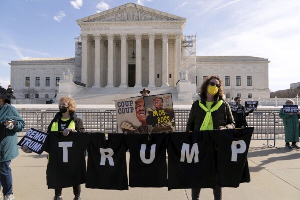 Những người biểu tình giương biểu ngữ bên ngoài Tòa án Tối cao Hoa Kỳ, Thứ Năm, ngày 8 tháng 2 năm 2024, tại Washington. Tòa án Tối cao Hoa Kỳ vào thứ Năm sẽ xét xử một vụ án lịch sử có thể quyết định liệu Donald Trump có đủ điều kiện tham gia cuộc bỏ phiếu năm 2024 theo Mục 3 của Tu chính án thứ 14 hay không. (Ảnh AP/Jose Luis Magana)