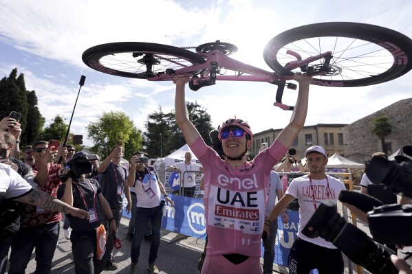 Slovenia's Tadej Pogacar, wearing the pink jersey of the race overall leader, holds his bike up as he celebrates after winning the 20th stage of the Giro d'Italia cycling race from Alpago to Bassano del Grappa, Italy, Saturday, May 25, 2024. (Fabio Ferrari/LaPresse via AP)