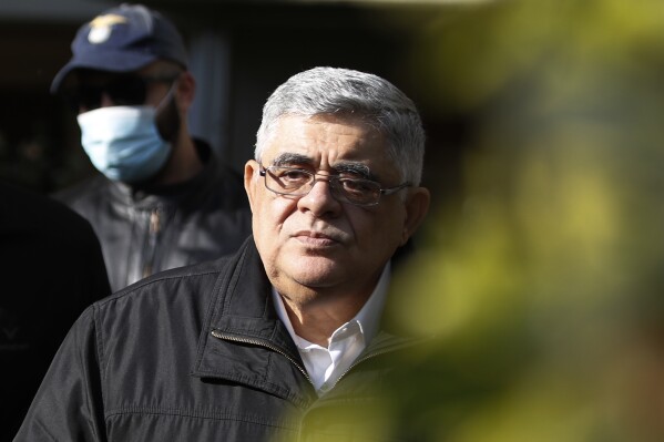 FILE - Golden Dawn party leader Nikolaos Michaloliakos, escorted by police officers leaves his residence in Athens, Oct. 22, 2020. The head of Greece’s extreme far-right Golden Dawn party will return to prison after a council of judges rescinded his early conditional release on Monday June 3, 2024. Nikos Michaloliakos was arrested in his Athens home following the decision, and will be taken back to prison just over a month after his release. (AP Photo/Thanassis Stavrakis, file)