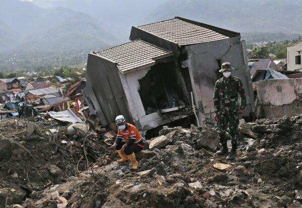 
              Rescuers rest near the ruin of a house at Balaroa neighborhood in Palu, Central Sulawesi, Indonesia, Thursday, Oct. 11, 2018. Indonesia's search for victims buried in neighborhoods annihilated by an earthquake and tsunami is nearing its end almost two weeks after the double disasters hit the remote city. (AP Photo/Dita Alangkara)
            