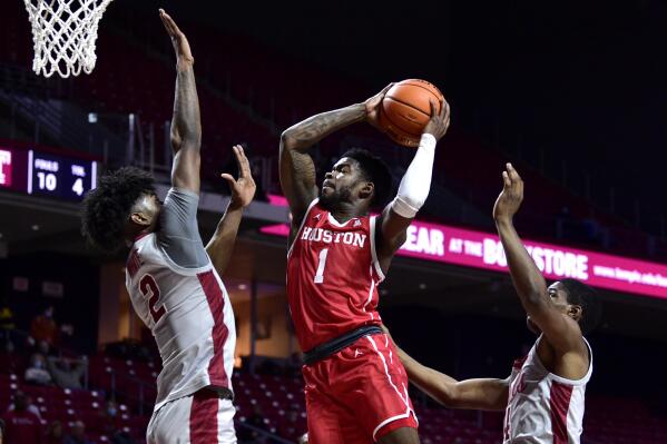 Houston's Jamal Shead (1) shoots past the defense of Temple's Jahlil White (2) and Hysier Miller during the first half of an NCAA college basketball game, Sunday, Jan. 2, 2022, in Philadelphia. (AP Photo/Derik Hamilton)