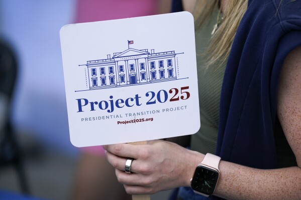 Kristen Eichamer holds a Project 2025 fan in the group's tent at the Iowa State Fair, Aug. 14, 2023, in Des Moines, Iowa. With more than a year to go before the 2024 election, a constellation of conservative organizations is preparing for a possible second White House term for Donald Trump. The Project 2025 effort is being led by the Heritage Foundation think tank. (AP Photo/Charlie Neibergall)